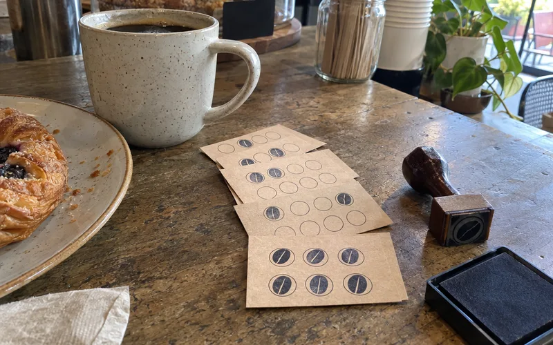Paper loyalty punch cards with ink stamps, a rubber stamp and an ink pad on a cafe counter