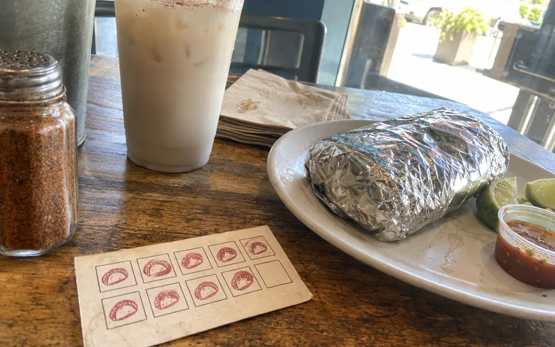 Stamped paper punch card next to a burrito on a restaurant table